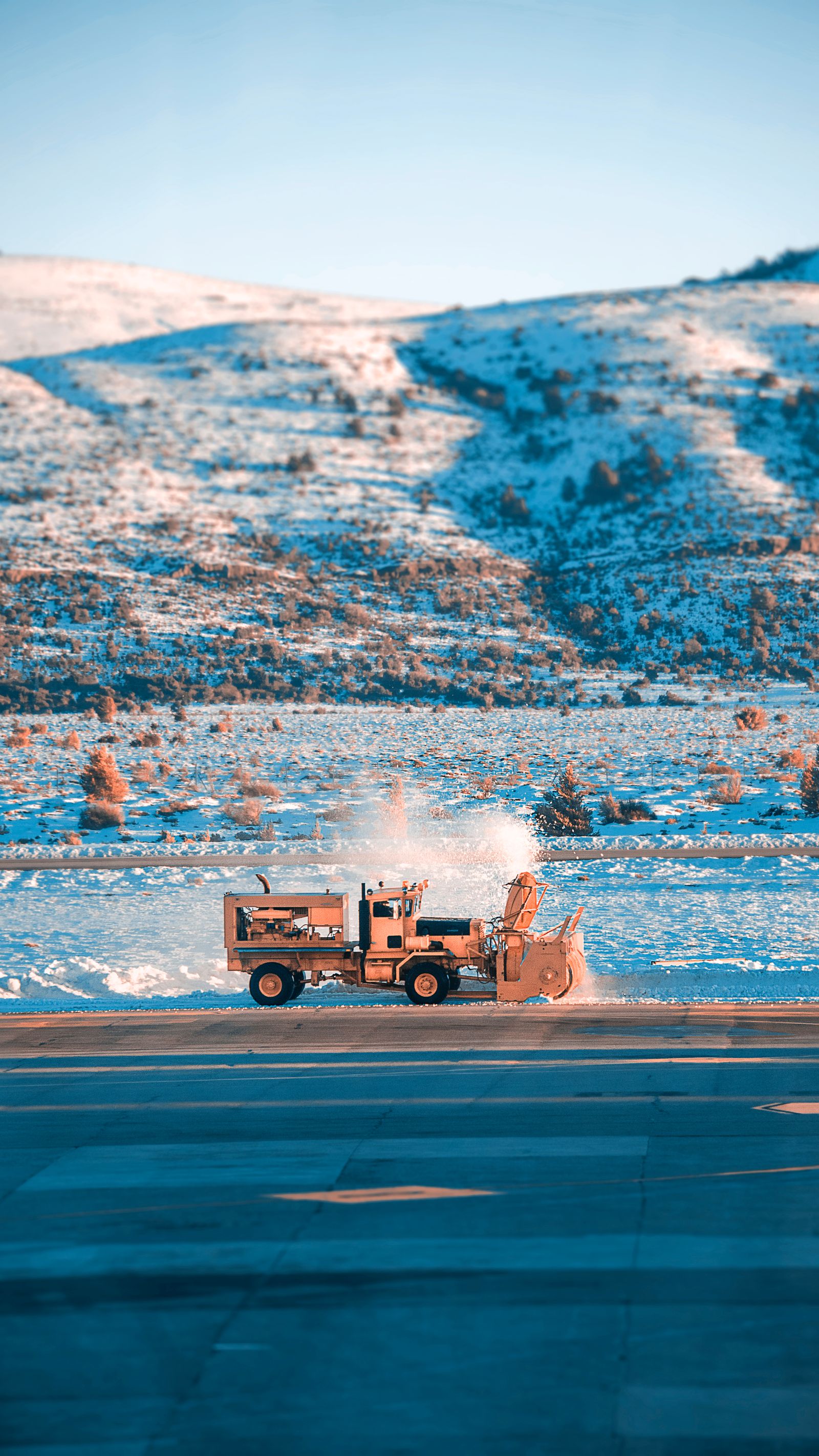 Snow plow working against a snowy mountain backdrop