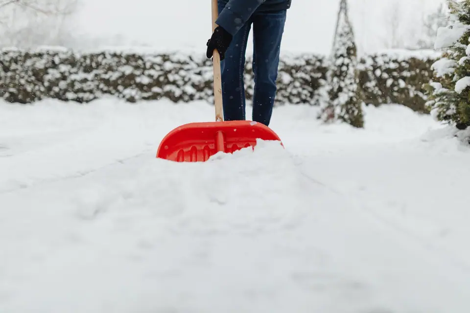 Red shovel pushing through fresh snow
